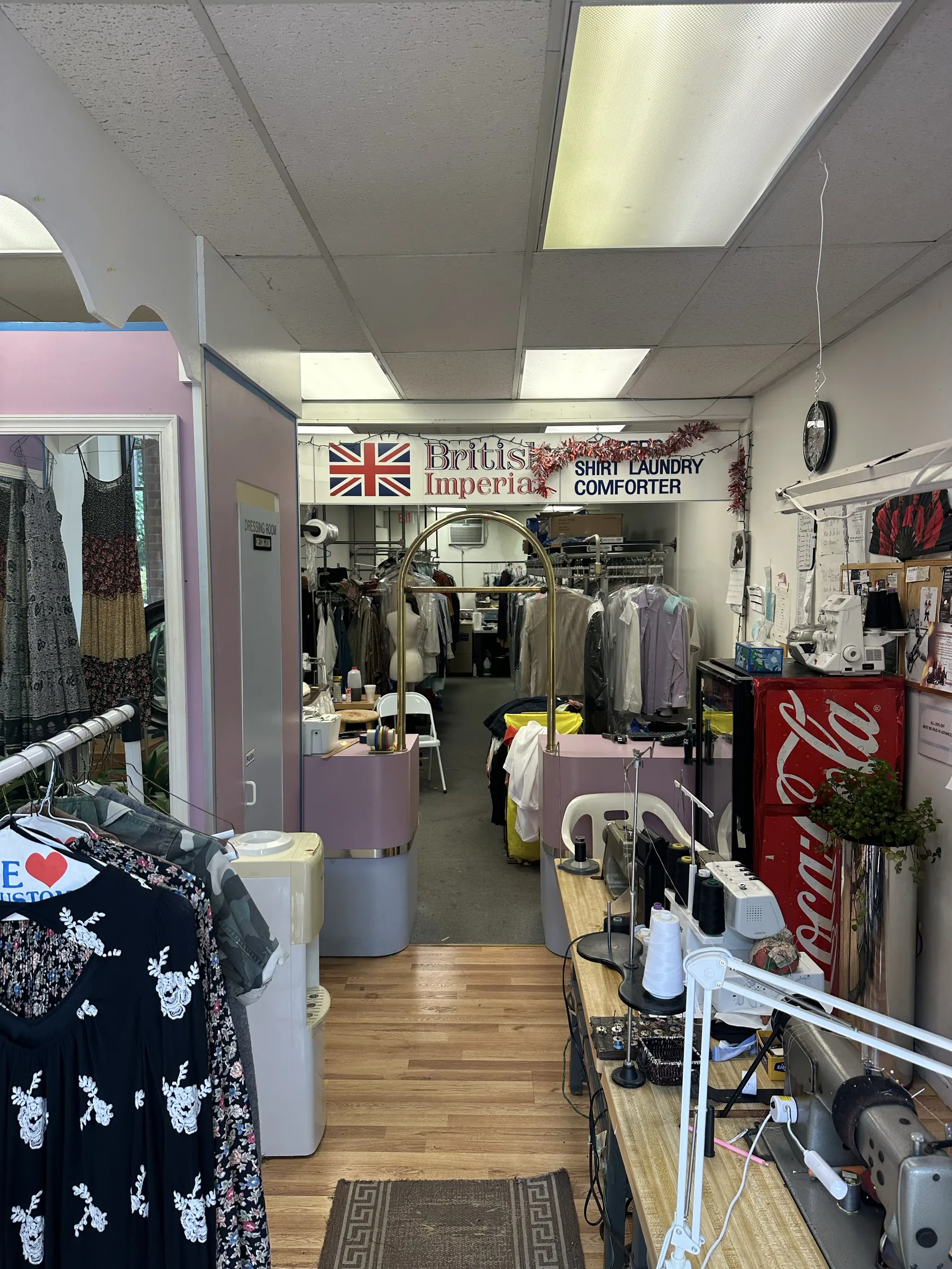 Interior of Sproul Cleaners with garment racks, sewing machines, and the service counter.