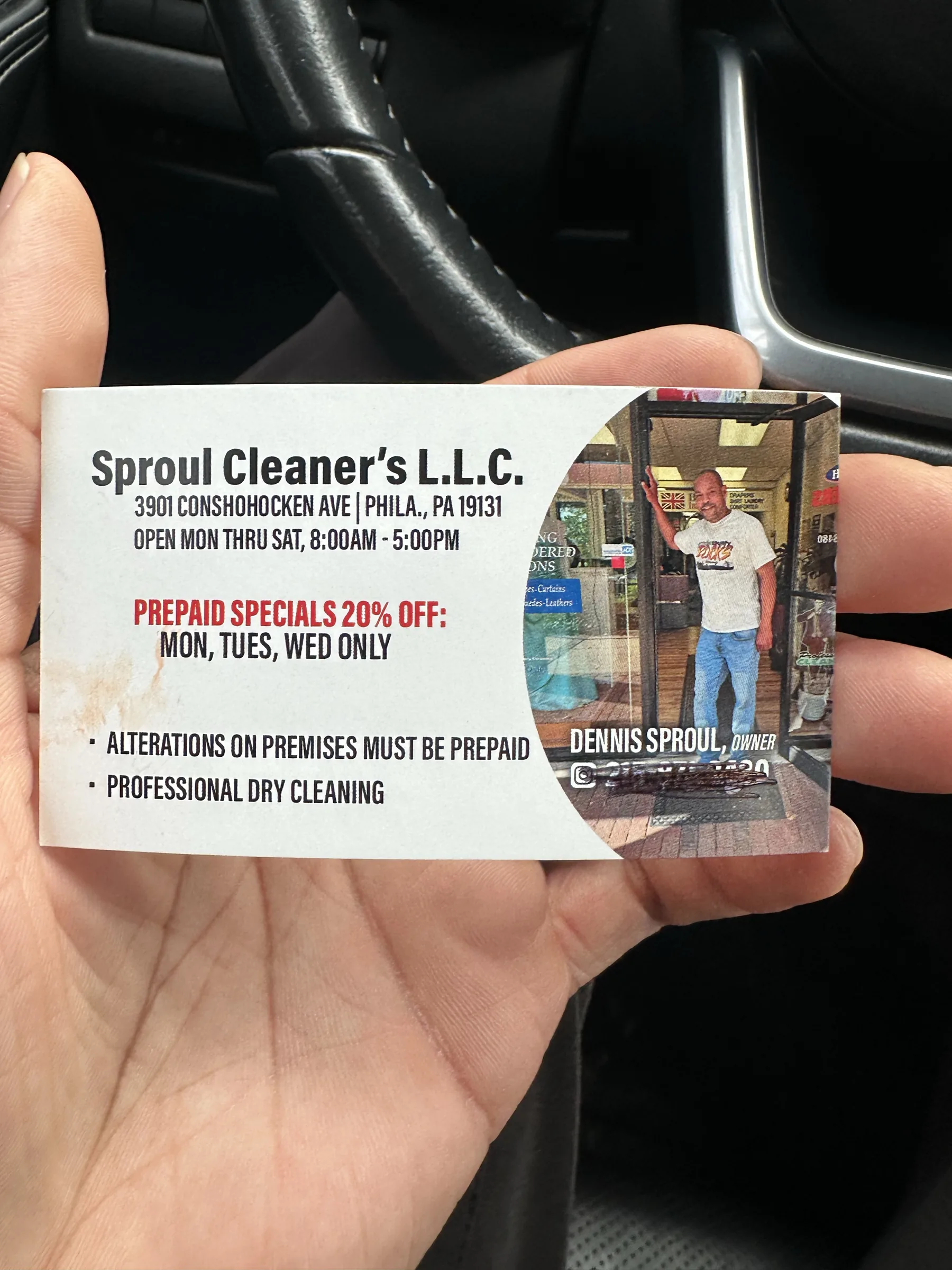 Sproul Cleaner's business card held in a hand, featuring owner Dennis Sproul and shop information.